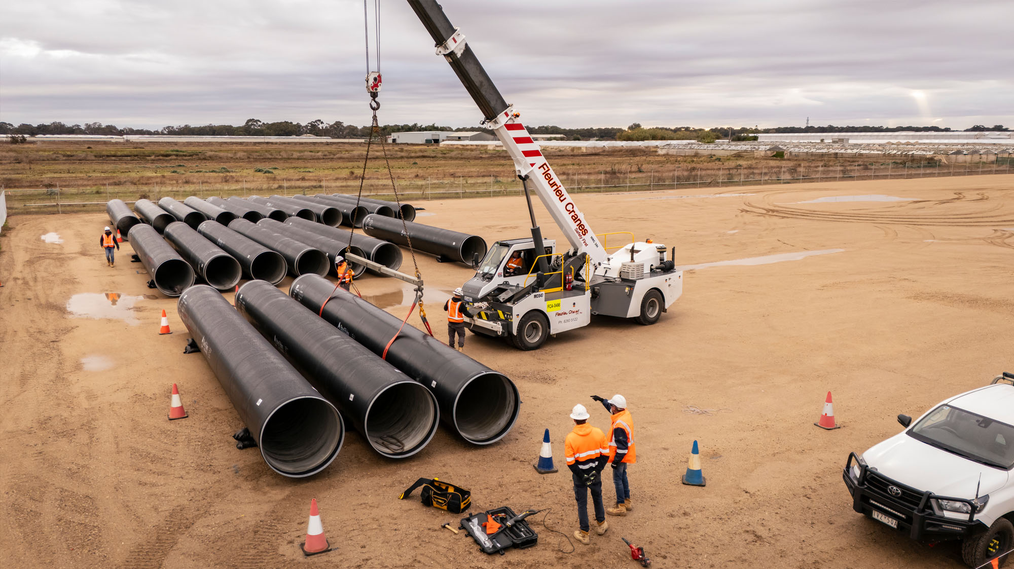 Pipes being delivered and laid our by a crane on a large development ste in Adelaide's north,